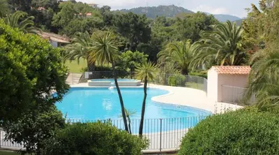 a swimming pool with a fence and palm trees at Favone Mini Villa Playa del Oro in Favone