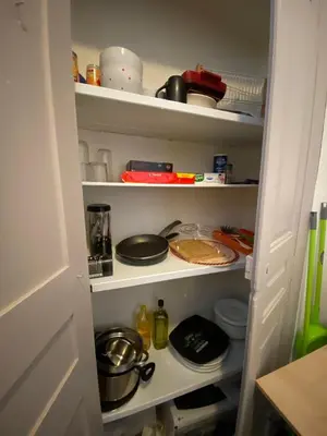 a kitchen pantry with dishes and pans on shelves at Charmant T1 plein centre Corte au 13 cours paoli wifi gratuit calme lumineux in Corte