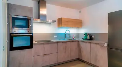 a kitchen with wooden cabinets and a sink at Solaneos propose magnifique T4 neuf sur le port avec Piscine CHAUFFEE in Porto-Vecchio