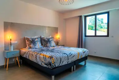 a bedroom with a king sized bed with a window at Solaneos propose magnifique T4 neuf sur le port avec Piscine CHAUFFEE in Porto-Vecchio