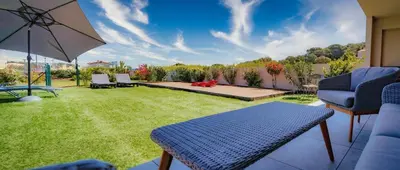 a backyard with a table and chairs and an umbrella at Solaneos propose magnifique T4 neuf sur le port avec Piscine CHAUFFEE in Porto-Vecchio
