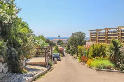 a road through a garden with a building in the background at Camping maeva Escapades Colomba in Olmeto