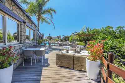 a deck with tables and chairs and palm trees at Camping maeva Escapades Colomba in Olmeto