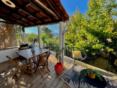 a patio with a table and chairs on a deck at Joli studio maisonnette à 100m de la plage in Porticcio