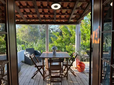 a screened in porch with a wooden table and chairs at Joli studio maisonnette à 100m de la plage in Porticcio