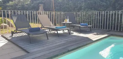 a deck with two chairs and a table next to a pool at Villa Ribba 10 pers piscine 5 min plage en voiture in Porto-Vecchio