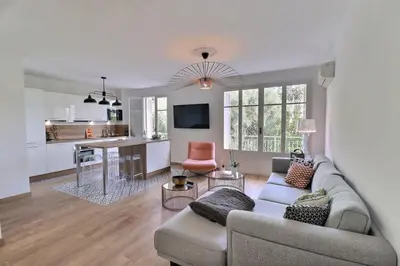 a living room with a couch and a kitchen at Charmant T2 avec balcon - Parking, AC, Wifi in Ajaccio