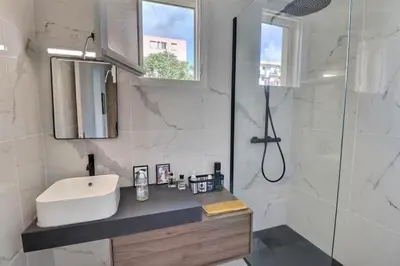 a white bathroom with a sink and a shower at Charmant T2 avec balcon - Parking, AC, Wifi in Ajaccio