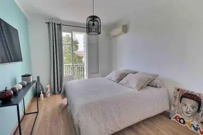 a white bedroom with a bed and a window at Charmant T2 avec balcon - Parking, AC, Wifi in Ajaccio