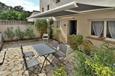 a patio with a table and chairs in front of a house at Appartement T2 Prunello By Intendance Excellency in Porto-Vecchio
