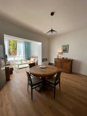 a living room with a wooden table and chairs at Appartement neuf, 2 chambres, climatisé, route des Sanguinaires in Ajaccio