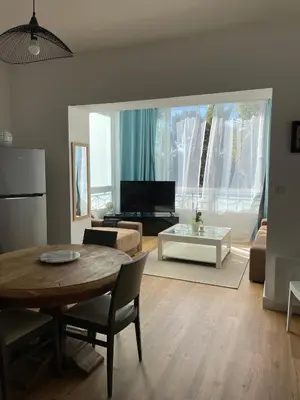 a living room with a table and a couch at Appartement neuf, 2 chambres, climatisé, route des Sanguinaires in Ajaccio