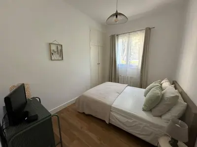a white bedroom with a bed and a television at Appartement neuf, 2 chambres, climatisé, route des Sanguinaires in Ajaccio