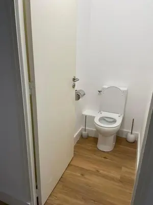 a white toilet in a bathroom with a wooden floor at Appartement neuf, 2 chambres, climatisé, route des Sanguinaires in Ajaccio