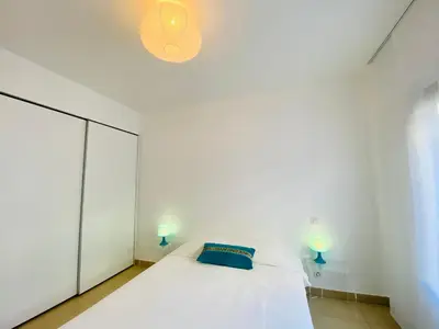 a white bedroom with a bed and two lamps at Les Jardins de Quatrina 2 chambres vue mer in Propriano
