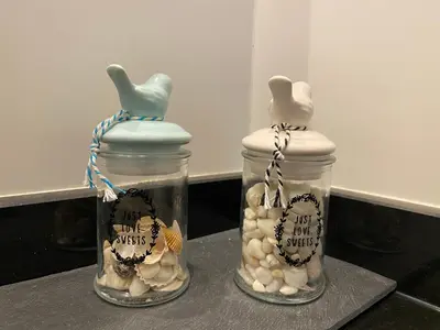 two glass jars filled with shells on a counter at Les Jardins de Quatrina 2 chambres vue mer in Propriano