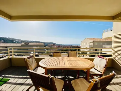 a table and chairs on a balcony with a view at Les Jardins de Quatrina 2 chambres vue mer in Propriano