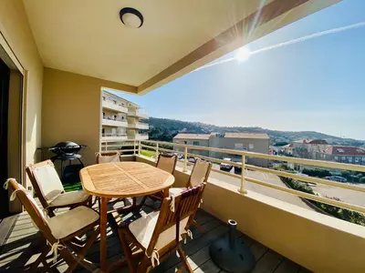 a balcony with a table and chairs and a view at Les Jardins de Quatrina 2 chambres vue mer in Propriano