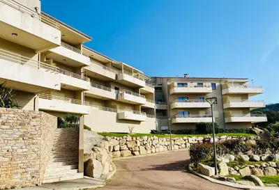 an apartment building with a street light in front of it at Les Jardins de Quatrina 2 chambres vue mer in Propriano
