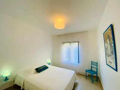 a bedroom with a white bed and a blue chair at Les Jardins de Quatrina 2 chambres vue mer in Propriano