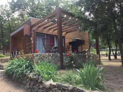 a tiny house with a stone wall and a pergola at Caselena , un havre de paix en Balagne in Ville-di-Paraso