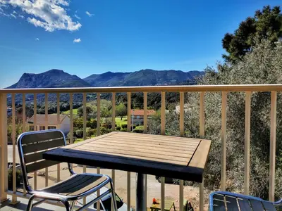 a wooden table and chairs on a balcony with mountains at Ustaria in Peri