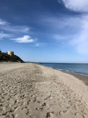 a sandy beach with a lighthouse in the distance at Mare e Monti in Aléria