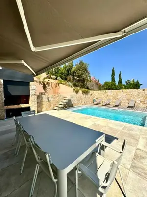 a table and chairs on a patio with a pool at Somptueuse villa d’architecte avec vue mer in Belvédère