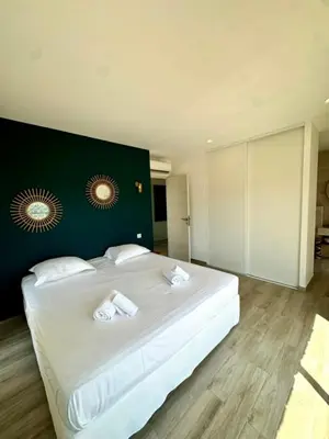 a bedroom with a large white bed with a green wall at Somptueuse villa d’architecte avec vue mer in Belvédère