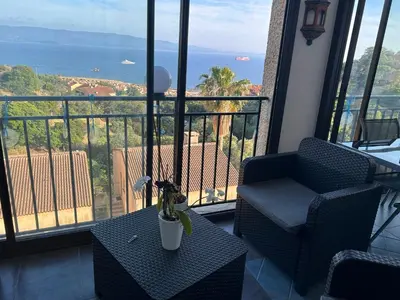 a living room with a table and chairs and large windows at Duplex F4-2 balcons face a la mer in Ajaccio