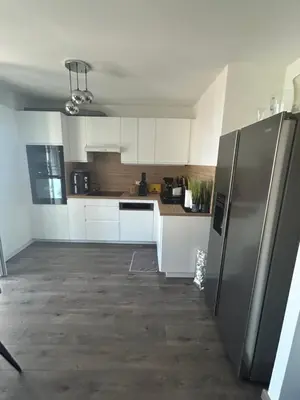 a kitchen with white cabinets and a stainless steel refrigerator at Duplex F4-2 balcons face a la mer in Ajaccio