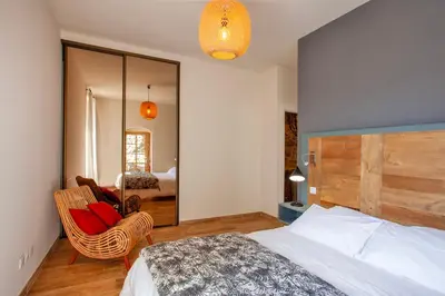 a bedroom with a bed and a chair and a mirror at Maison de Charme-A STALLA- Entre Mer et Montagne in Muro