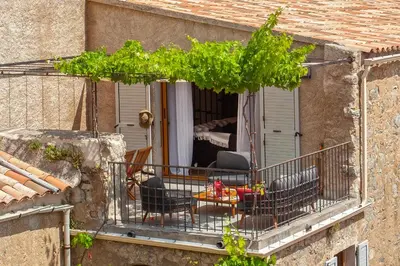 a balcony of a house with a table and chairs at Maison de Charme-A STALLA- Entre Mer et Montagne in Muro