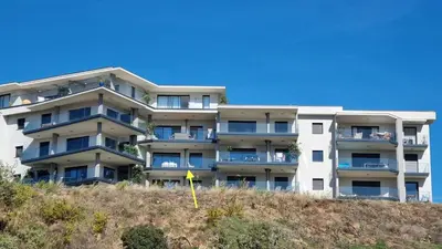 an apartment building on top of a hill with a yellow flag at Agosta Sea View in Porticcio