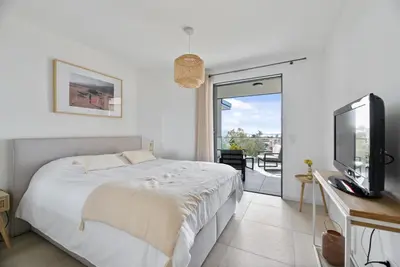 a bedroom with a bed and a tv and a balcony at Agosta Sea View in Porticcio