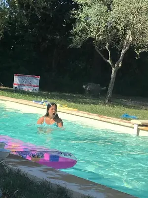 a woman in a swimming pool with a surfboard at gite au paradis, parc animalier in Olmeta-di-Tuda