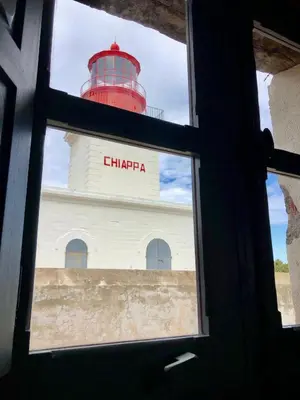 a view of a lighthouse through a window at La Chambre du Phare à Porto-Vecchio, unique ! in Porto-Vecchio