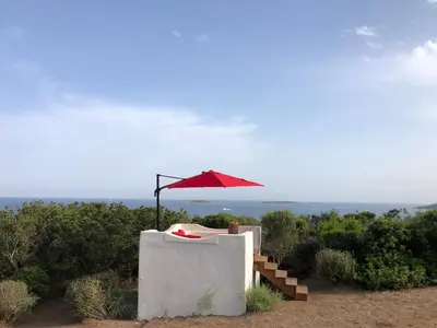 a red umbrella sitting on top of a building with a chair at La Chambre du Phare à Porto-Vecchio, unique ! in Porto-Vecchio