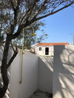 a shower on a wall next to a tree at La Chambre du Phare à Porto-Vecchio, unique ! in Porto-Vecchio