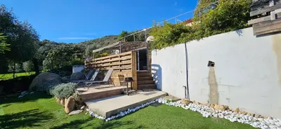 a house with a garden with a bench on the grass at Mini villa T3 climatisée, vue mer, cosy & moderne in Olmeto