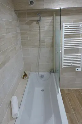 a bathroom with a bath tub with a shower at Mini villa T3 climatisée, vue mer, cosy & moderne in Olmeto