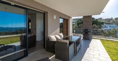 a patio with a couch and a table at Les Rivages de Stagnola Appartement T3 vue mer et montagne plage 200m climatisé in Pietrosella