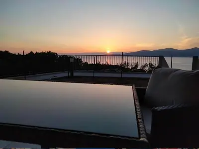 a couch sitting on a balcony with the sunset at Les Rivages de Stagnola Appartement T3 vue mer et montagne plage 200m climatisé in Pietrosella