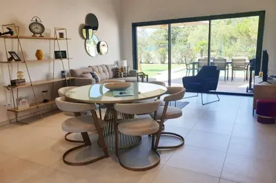 a living room with a table and some chairs at Villa 5***** piscine proche de la plage Cala Rossa in Lecci
