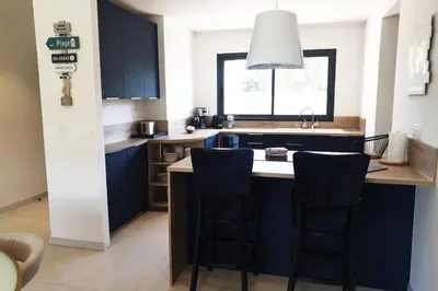 a kitchen with blue cabinets and two bar stools at Villa 5***** piscine proche de la plage Cala Rossa in Lecci