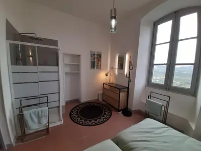 a bedroom with a bed and a dresser and two windows at F3 FENETRE SUR JARDIN VUE MER ET MONTAGNE pour 4 VOYAGEURS in Ajaccio