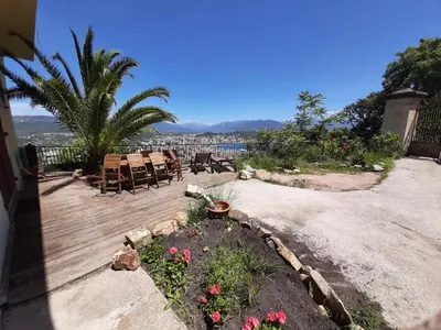 a wooden deck with chairs and flowers in a yard at F3 FENETRE SUR JARDIN VUE MER ET MONTAGNE pour 4 VOYAGEURS in Ajaccio