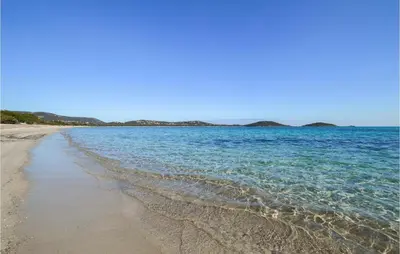 a sandy beach with water and trees in the background at Cala Di Mare in Lecci