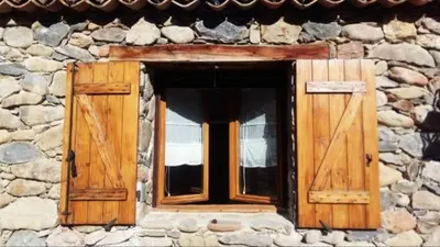 a window in a stone building with wooden doors at Les Bergeries de Piazzagina in Piediquarciu