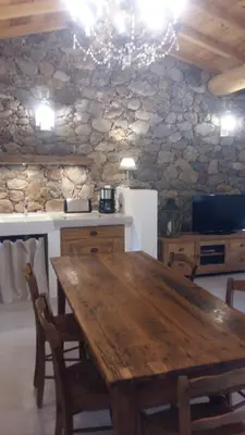 a wooden table in a kitchen with a stone wall at Les Bergeries de Piazzagina in Piediquarciu